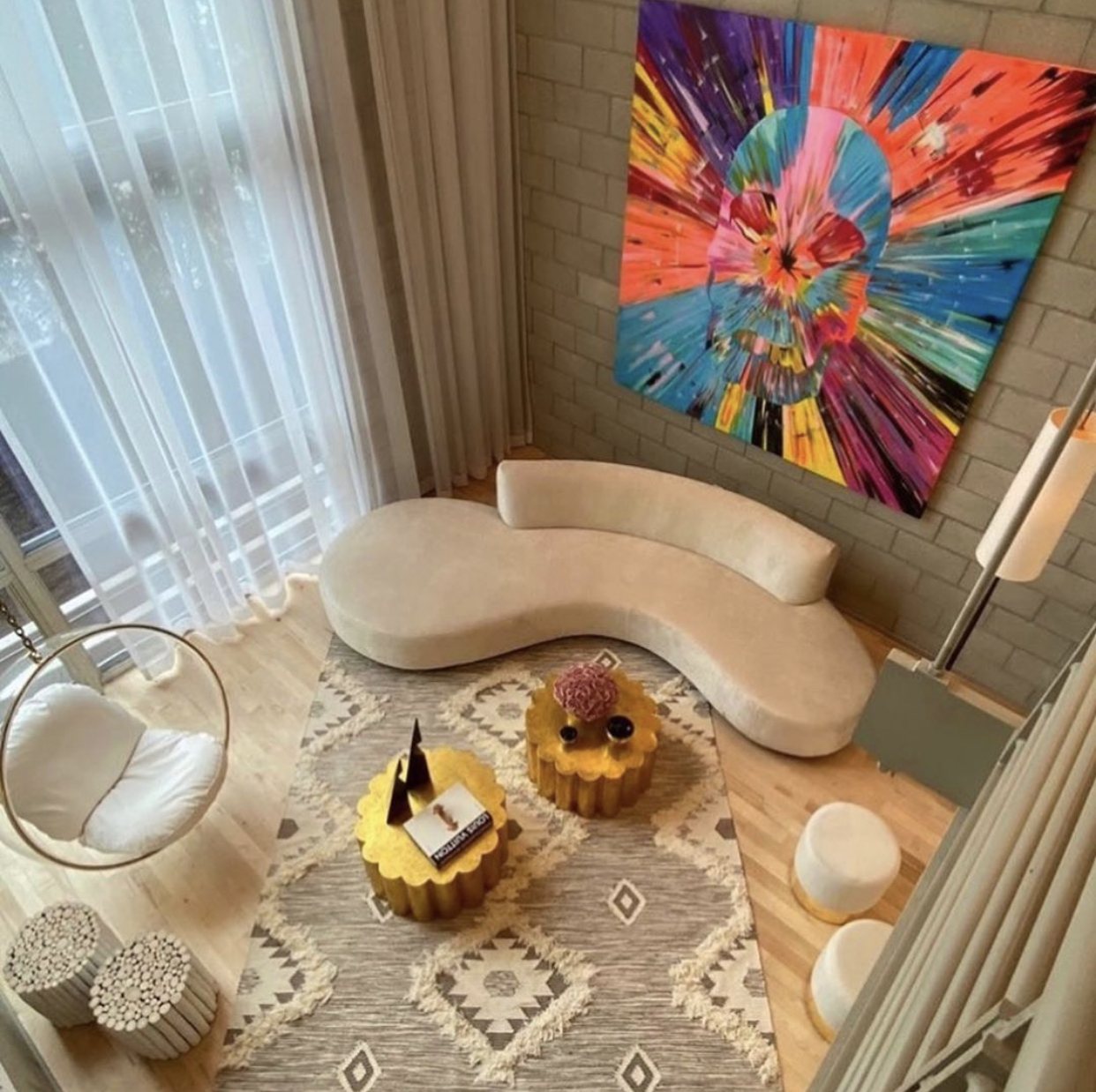 Large multicolour spin painting of a skull above a curved sofa