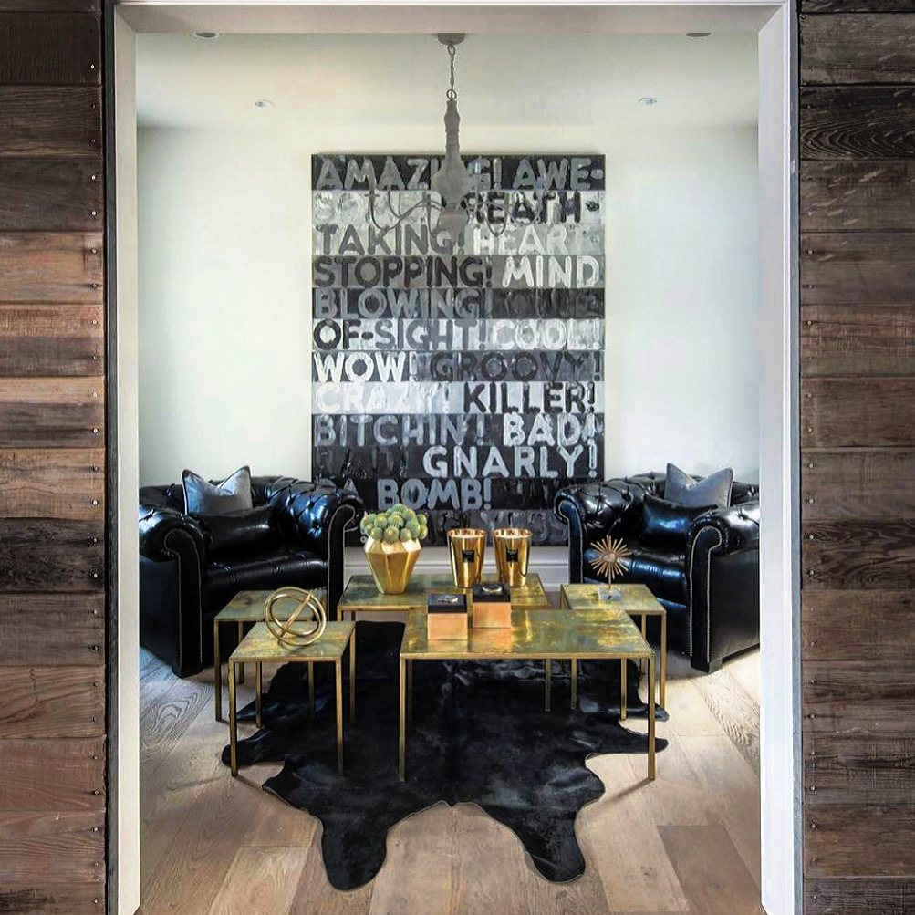 Black and silver text painting between two black leather armchairs